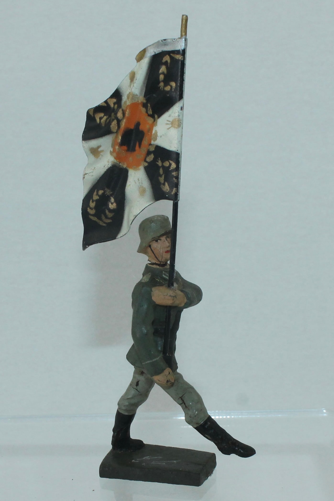 Lineol Traditions Flag Goose Stepping: 5/33/1. Looking Right with Traditions Flag in Black and White. Made 1937-40. 1 Piece. Condition Very Good to Excellent. Crack in Neck. No Box.