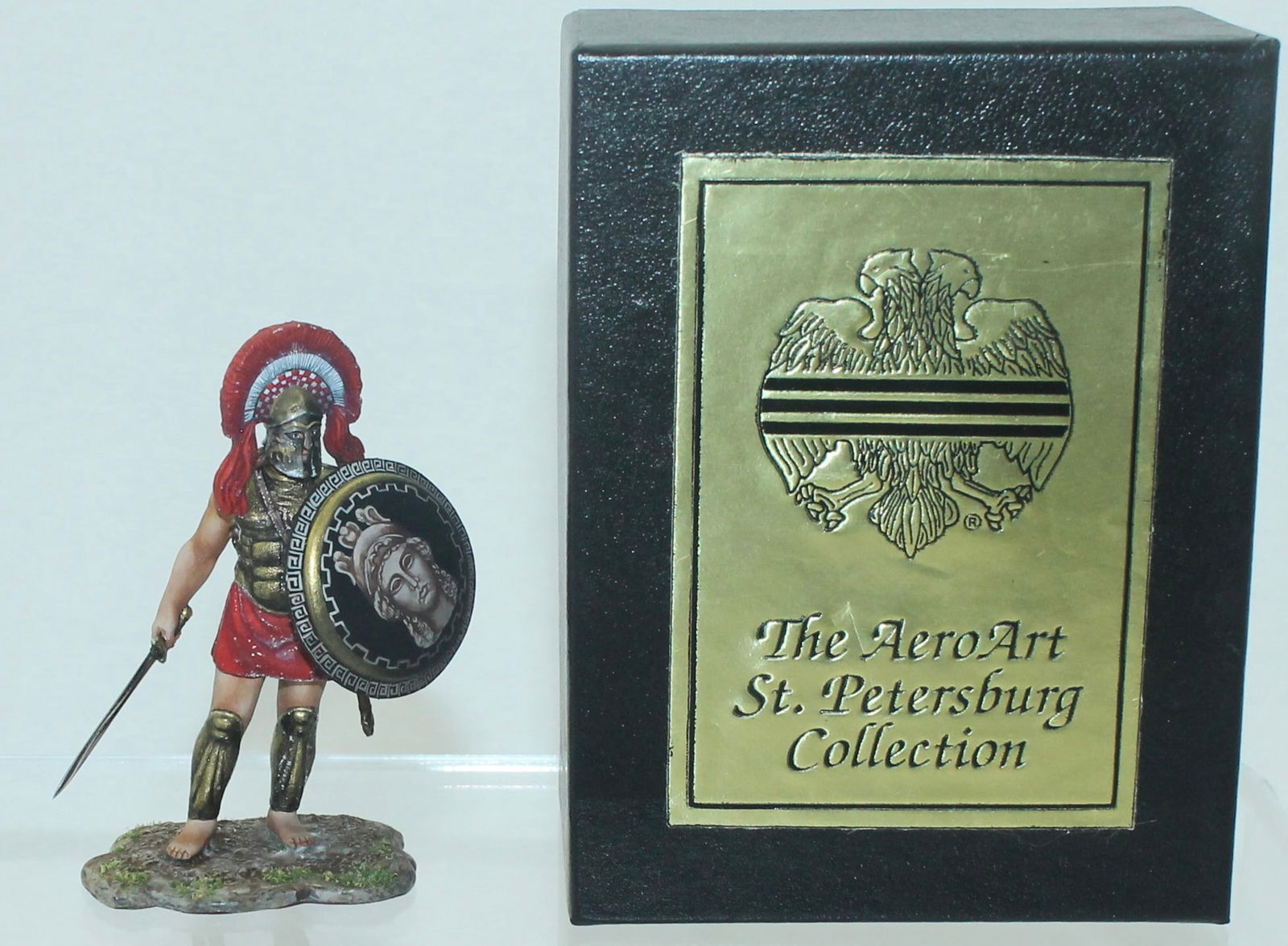 Aero Art Greek Warrior Standing with Shield: St. Petersburg Collection. Aspis with Goddess. 6286.2 on Underside of Base. 1 Piece. Condition Very Good to Excellent. Some Areas of Oxidation to Paint. Box Very Good.