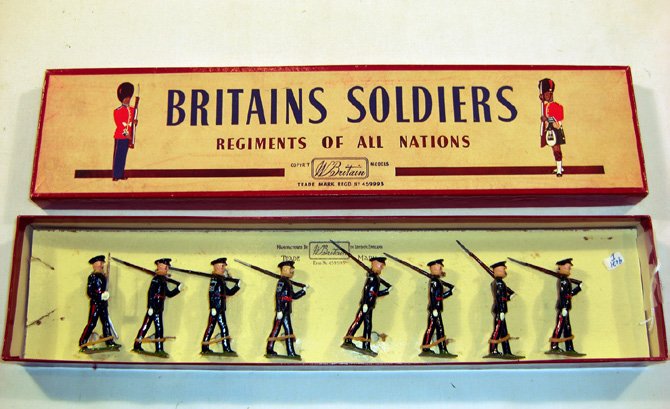 Britains: Set #2089 The Gloucestershire Regiment: Post-War. No 1 dress, marching at the slope, 7 infantry 1 officer in original “Regiments” box (NM, mismatched, boxVG) (8). Added Chevrons & Arm stripes.