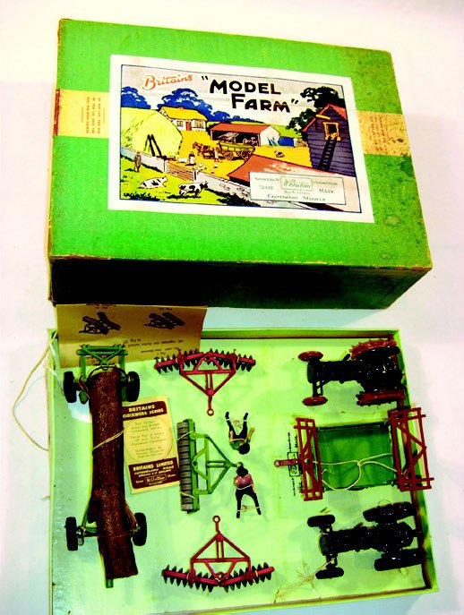 Britains: Extremely Rare Farm Set #134F: Tractors and Implements. Comprising 2 blue tractors, 1 trundle trailer, 2 disc harrows, 1 roller, 1 timber trailer with timber, 2 tractor drivers. Tied in original box with instructions, box has compa