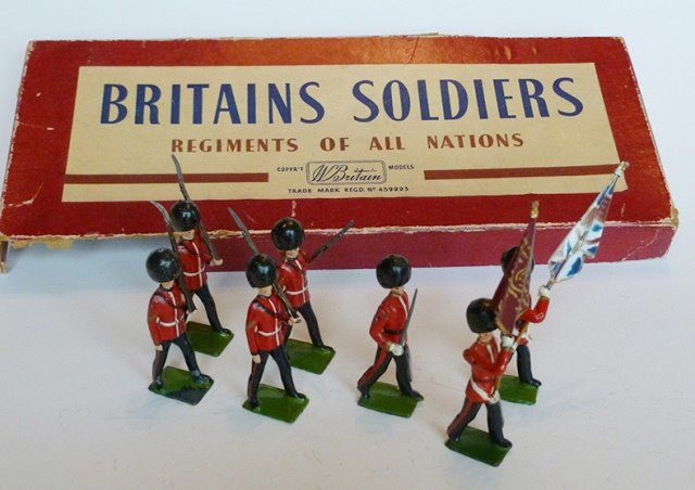 Britains Set #2084 Scots Guards Colour Party: Post War. First Version 1954-1959. 7 pieces. With original R.O.A.N. box. No tie card. Condition excellent. Box very good. (portion of edge of lid missing)
