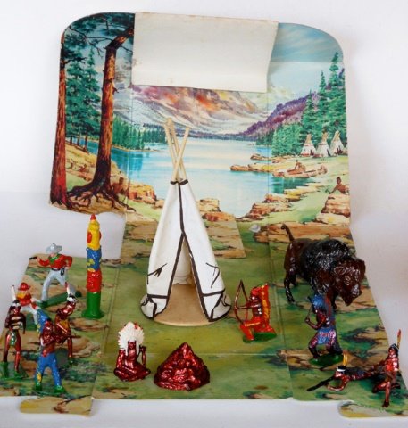 Johillco Wild West Playpack Display: Post War. With original scenic backdrop box. Including totem pole, wigwam, buffalo, campfire, 8 Indians and 2 cowboys. 14 pieces. Condition excellent. Box excellent.