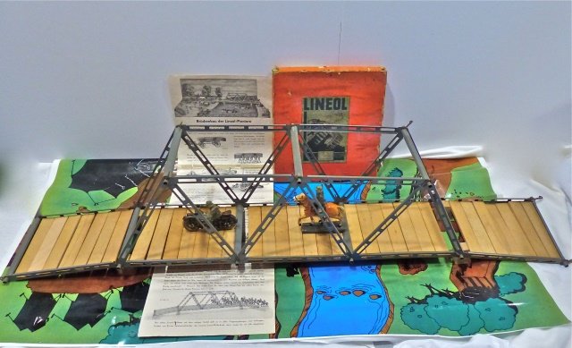 Lineol 3 Span Bridge+Box+2 Figs+Layout Sheet: Bridge is complete and all original. The box shows some edge wear but the Lineol logo in the center is complete. The Lineol motorcycle shows wear and has a few cracks. The mounted soldier and horse ha