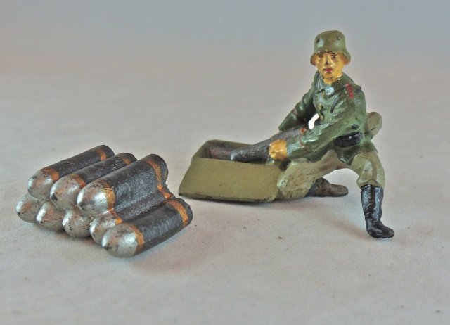 Lineol Artillery w/Cartridge Case+Shell Stack: Soldier has no cracks and hardly any wear. Face and paint quality are excellent. The shell stack is complete with no cracks and hardly any wear. 2 pieces. Soldier made 1936-39. Shell stack 1934-39. Co