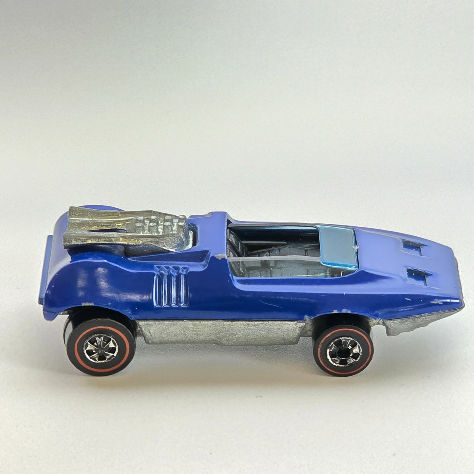Hot Wheels Redline Peeping Bomb: Enamel Peeping Bomb - Dark Blue - Dark interior Good condition overall, has scattered chips and hard edge wear as seen. Glass is crack free. Wheel chrome is very good with light wear in spots. Base is