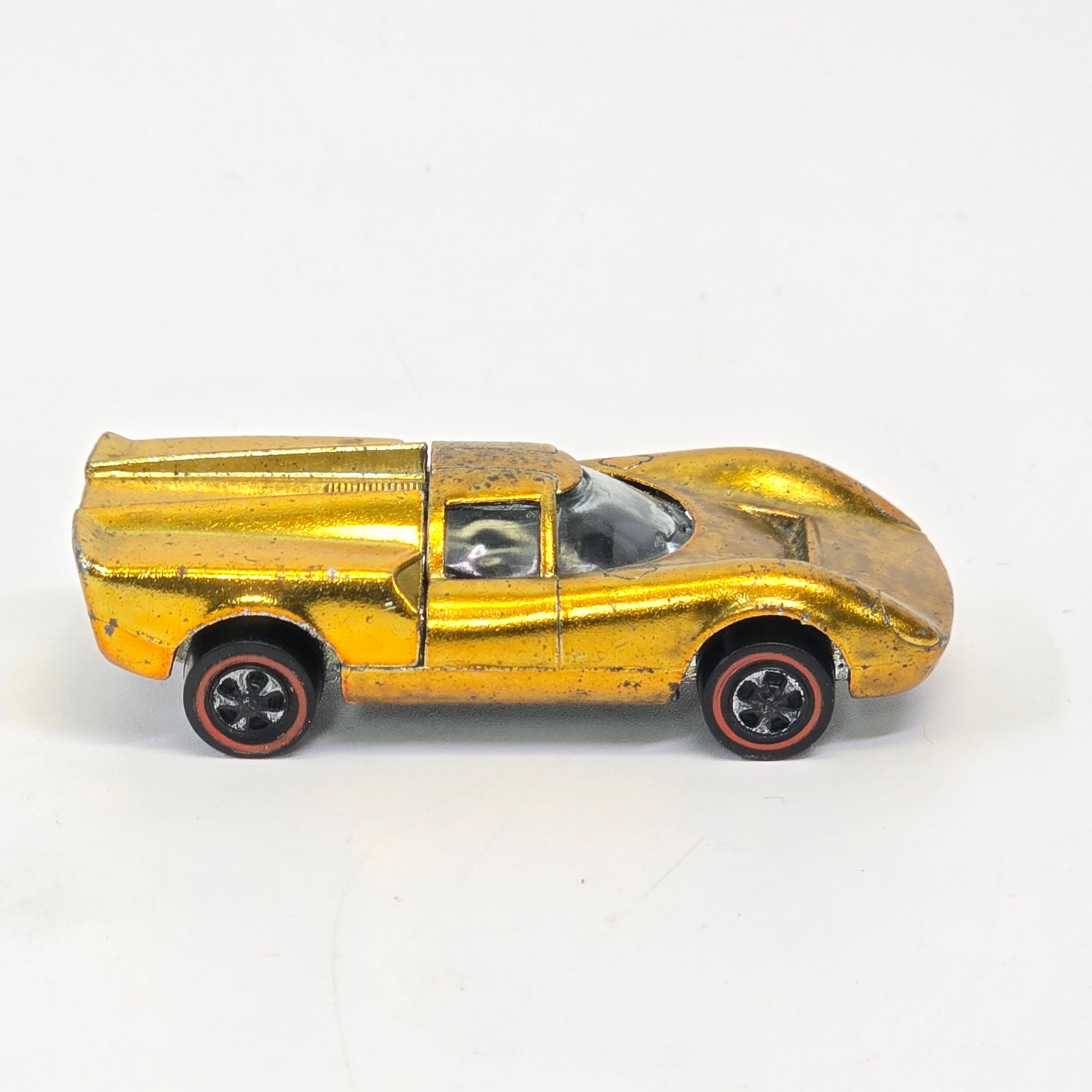 Hot Wheels Redline Lola gt70: Hot Wheels Redline US Lola Gt70 - Gold Overall car is good with hard edge wear in spots as seen. Has toning and mottle to paint as seen. Wheels are worn with most of chrome gone, base has 