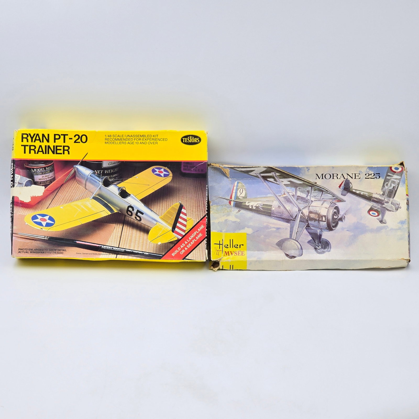 Pair of Plane Model Kits: Pair of Plane Model Kits, one being Testors and one being Heller. Both have box and look to be unassembled. 1- Ryan PT- 20 Trainer (1983)- most pieces are not attached to a tree and unclear if complet