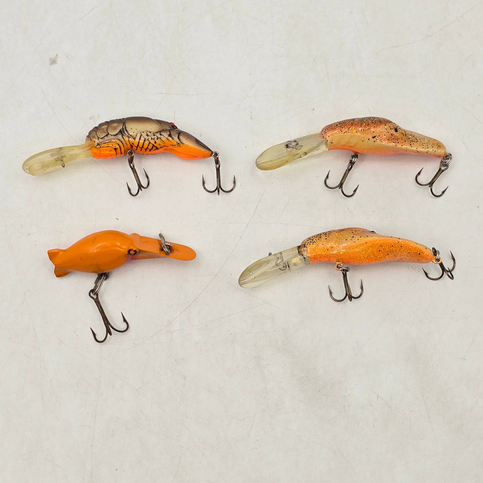Crankbait Fishing Lures 4pc: Lot of 4 Crankbait Fishing Lures. Includes an assortment of diving crankbait-style lures in orange and natural patterns. Lures show signs of use including wear and some hook