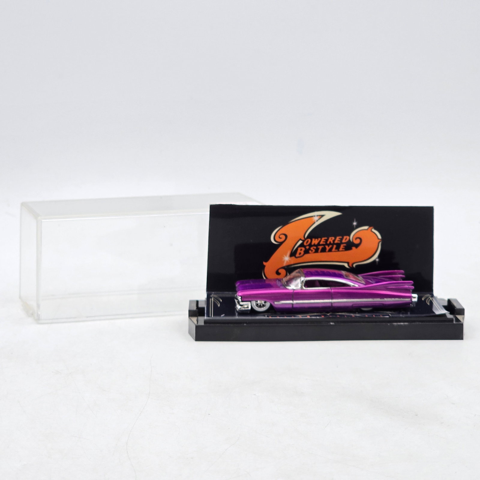 Lowered & Style Custom Lowrider Display: Custom lowrider-style diecast display featuring deep metallic purple paint, chrome trim accents, and â€?Lowered & Styleâ€? themed presentation artwork. Produced as part of the Kustom