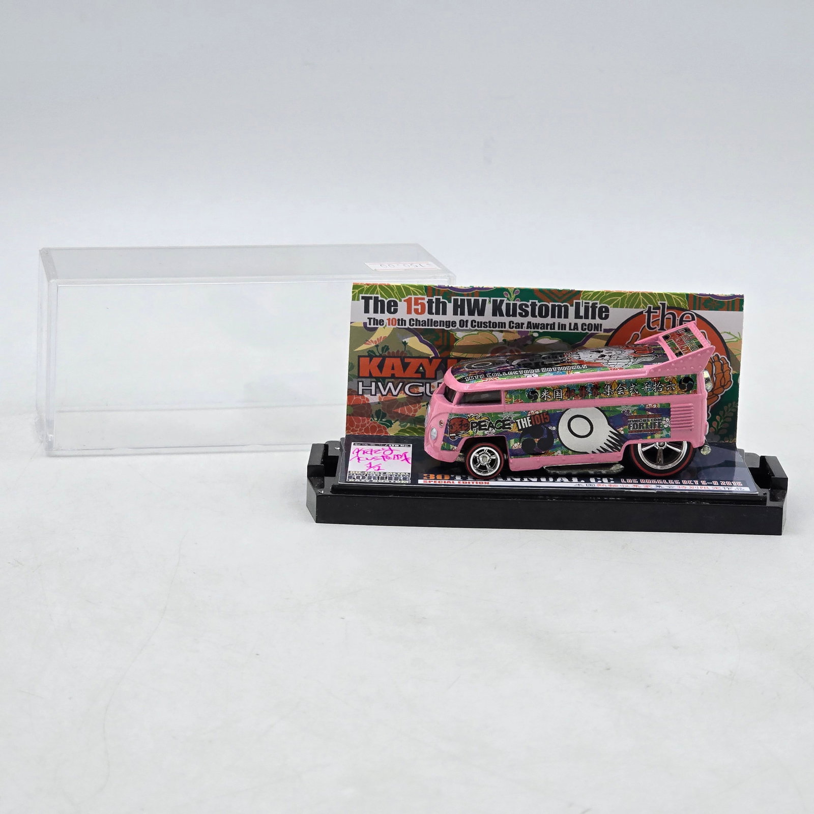 Kazy Kustom THE1015 Pink VW Drag Bus: Custom Volkswagen-style Drag Bus by Kazy Kustom featuring bright pink paint, multicolor holographic-style graphics, and raised drag-style rear wing. Artwork references THE1015 and the 30th Annual H.W.