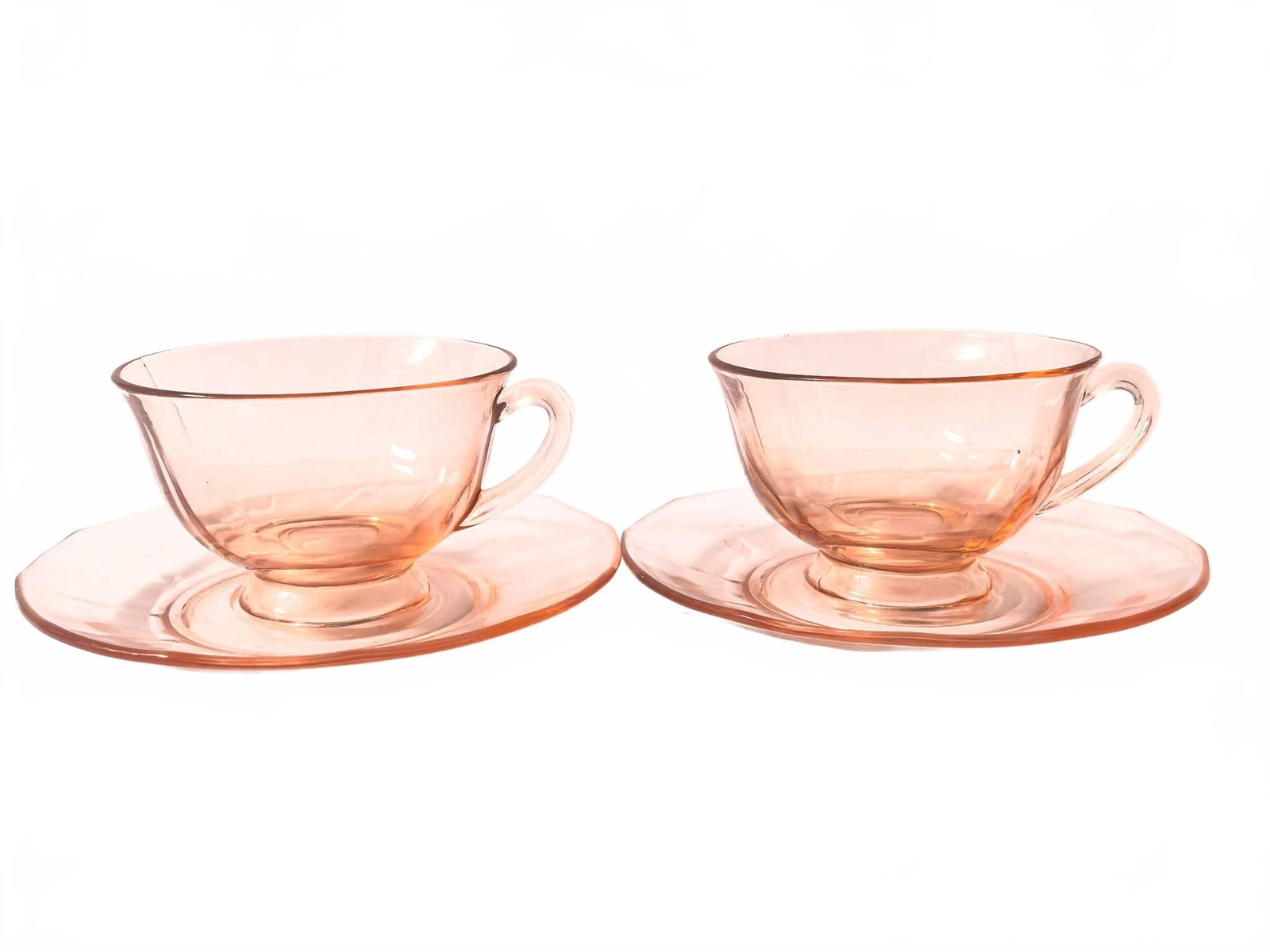 Pair Pink Depression Glass Cups and Saucers: Two matching pink glass teacups with handles and two coordinating saucers. 5.75in