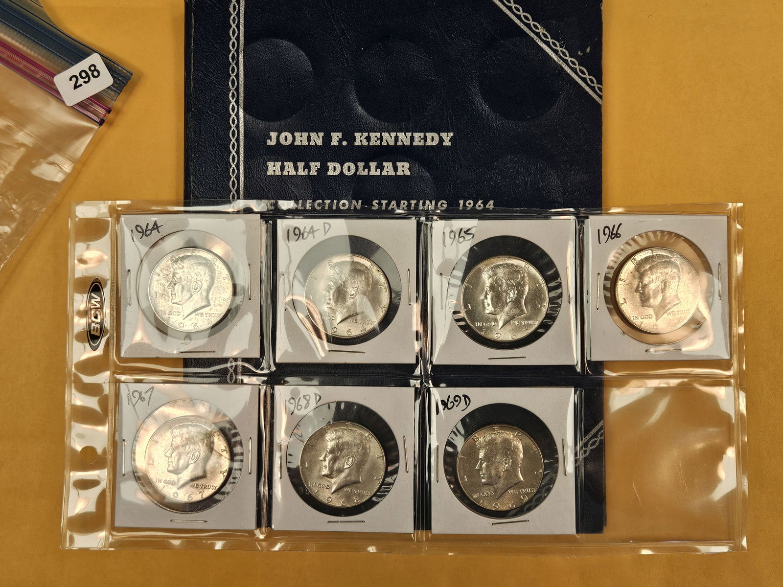 Kennedy half dollar collection: Empty Whitman folder with seven silver Kennedy half dollars. Two 90% and five 40% silvers 