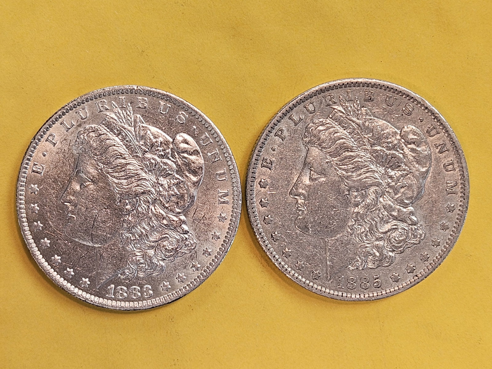 Two About Uncirculated plus Morgan silver Dollars: 1883-O and 1885-O