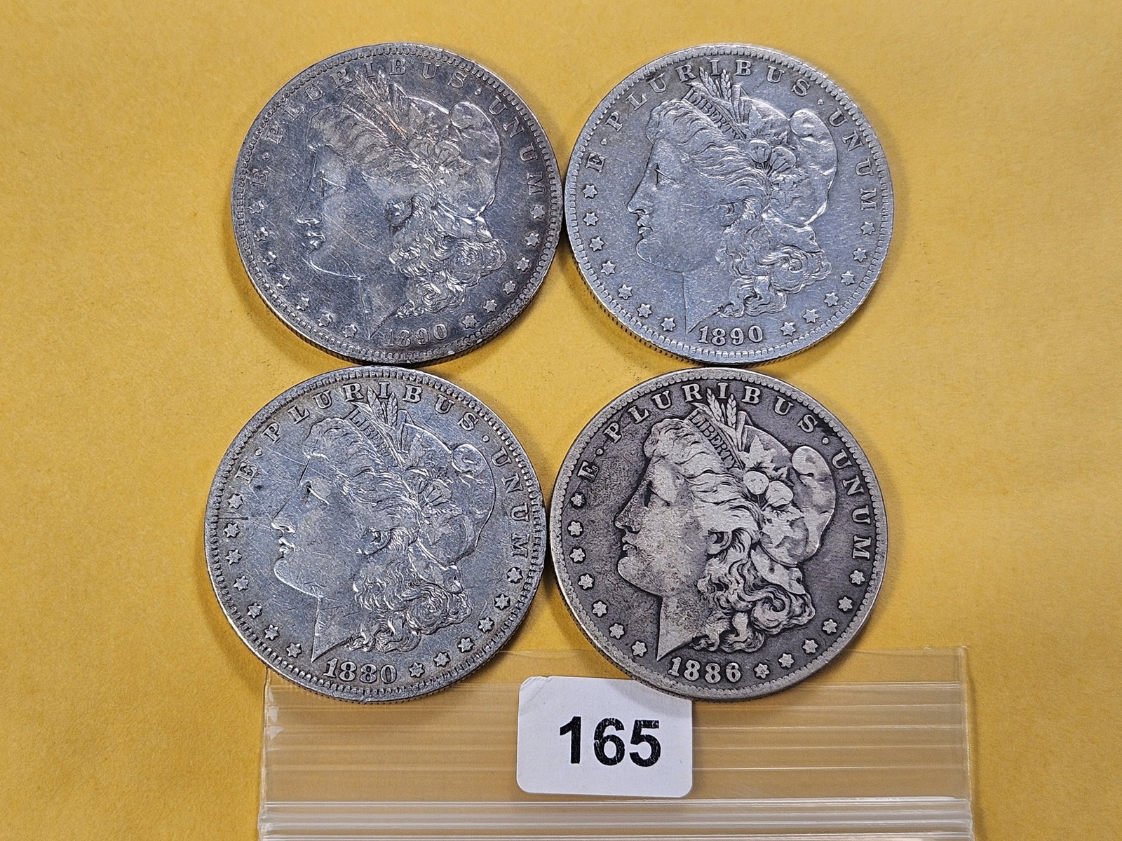 Four Morgan Silver Dollars: 1880-O, 1886-S and two 1890-O