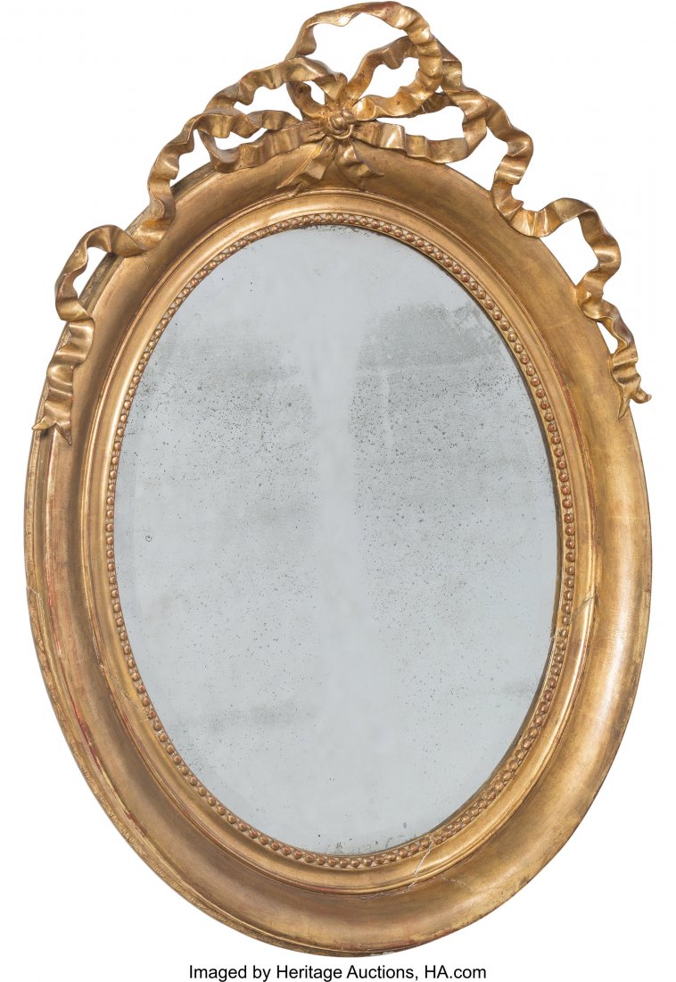 A Louis XVI-Style Carved Giltwood Oval Mirror wi: A Louis XVI-Style Carved Giltwood Oval Mirror with Ribbon Pediment, 19th century 41-3/4 x 3