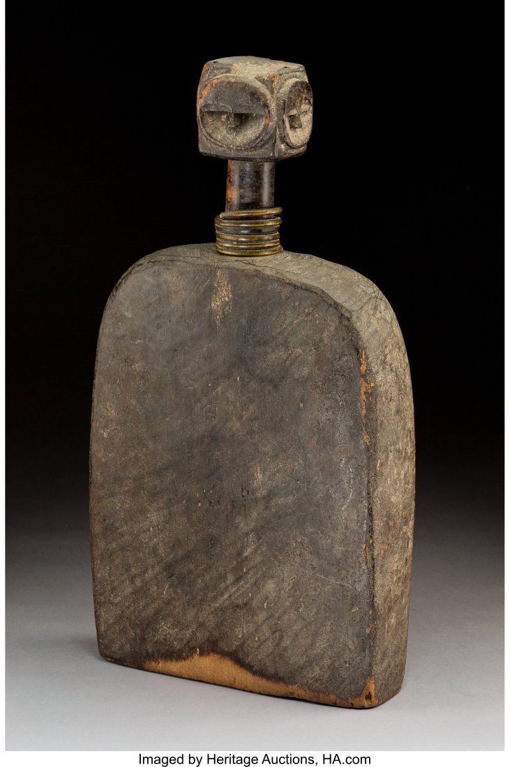 An Eket Drum Nigeria Blackened wood with four : An Eket Drum Nigeria Blackened wood with four faces on knob of handle, the neck of handle with metal coil. Provenance: Dr. & Mrs. John Finley Purchased 05/24/1989 from Davis Gallery, New Orleans, 