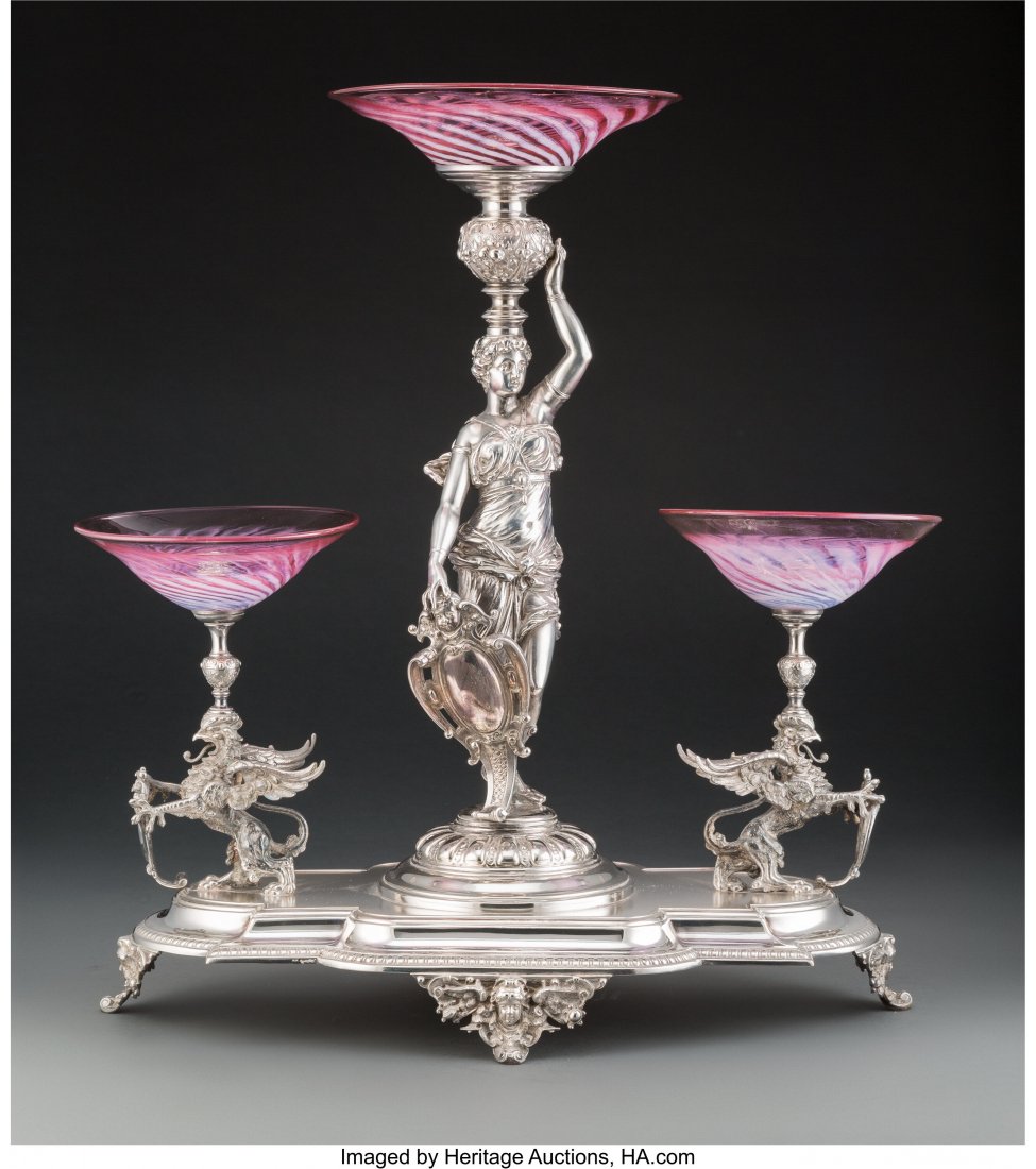 A Continental Silver-Plated Figural Epergne with: A Continental Silver-Plated Figural Epergne with Pink Glass Dishes, 20th century 21 x 19 x 11-1/2 inches (53.3 x 48.3 x 29.2 cm) The largest glass dish with fine one-inch scratch to interior well near