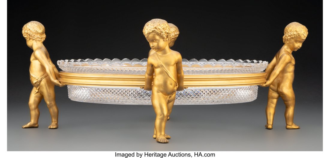 A Baccarat Gilt Bronze and Cut-Glass Cherubs Cen: A Baccarat Gilt Bronze and Cut-Glass Cherubs Centerpiece, early 20th century Marks: BACCARAT, (goblet-decanter-cup) 8 x 21 x 15-1/2 inches (20.3 x 53&period
