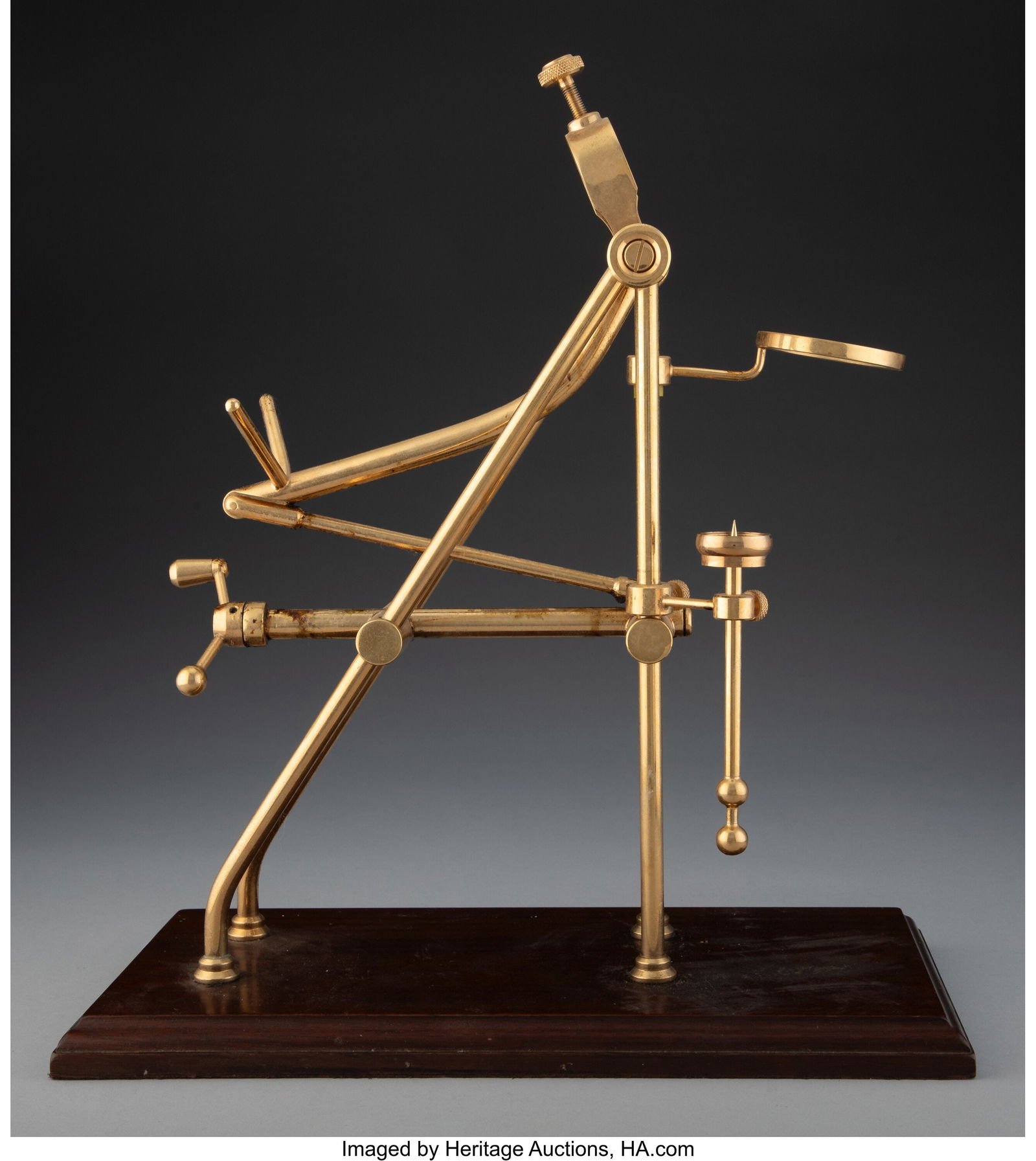 A Brass Wine Cradle on a Wood Base, 20th century: A Brass Wine Cradle on a Wood Base, 20th century 16-1/4 x 13-3/4 x 7-1/4 inches (41.3 x 34.9 x 18.4 cm) Property from the Collection of Frederick H&per