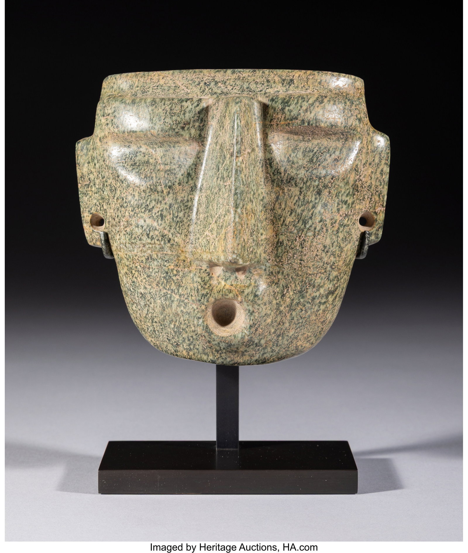 A Mezcala/Sultepec Mask Mexico, c. 500–100 BC: A Mezcala/Sultepec Mask Mexico, c. 500–100 BC Carved from speckled green hardstone, this mask presents a highly distinctive face, animated by its open mouth and extr