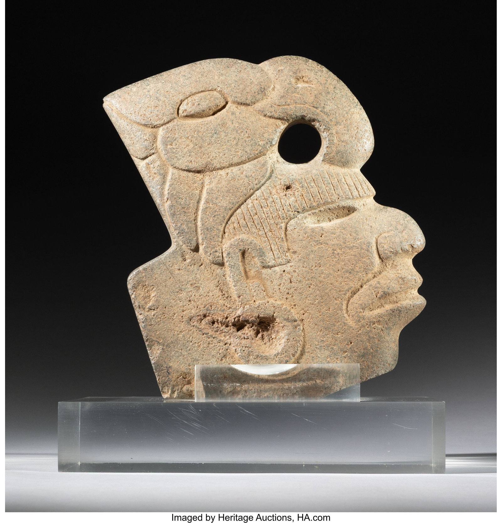 A Gulf Coast Hacha Mexico, c. 600–900 AD C: A Gulf Coast Hacha Mexico, c. 600–900 AD Carved from dense speckled gray-green hardstone, this hacha takes the form of a middle-aged human head wearing a large avian headdress