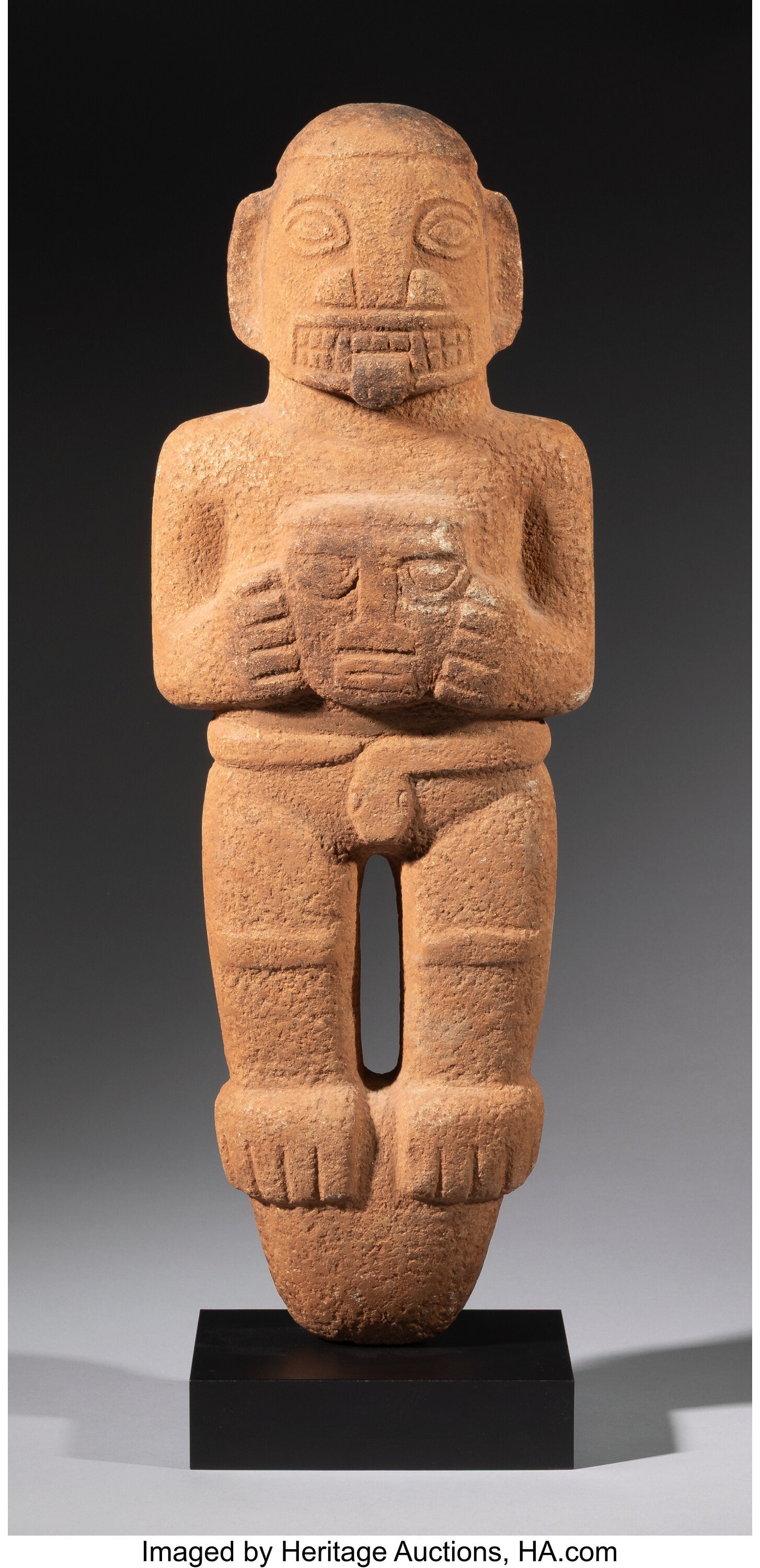 A Diquís Peg-Base Figure Costa Rica, c. 800–: A Diquís Peg-Base Figure Costa Rica, c. 800–1522 AD Carved from volcanic stone, the figure stands on an inverted conical peg base and holds a severed head before the bo