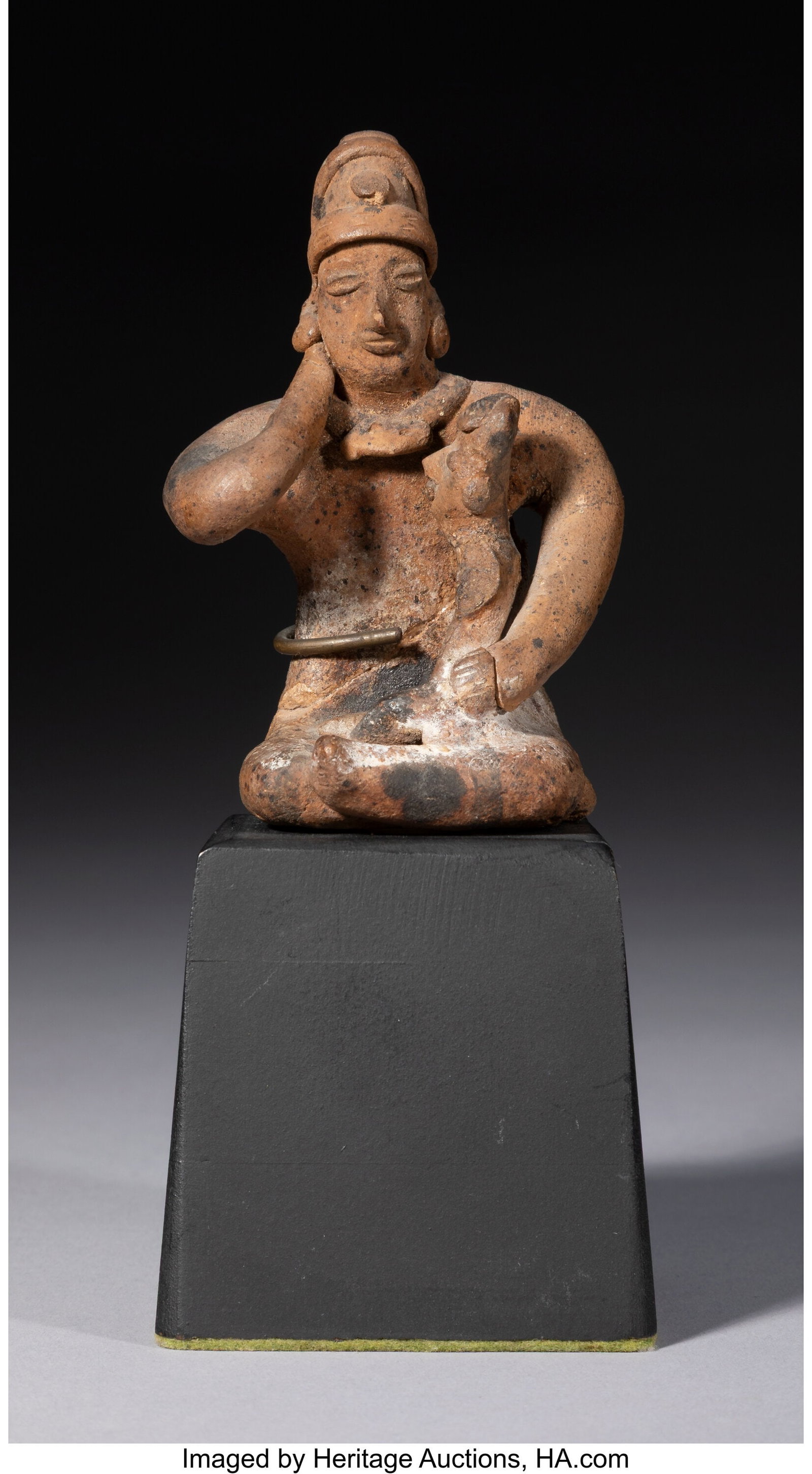 A Colima Figural Group: A Colima Figural Group West Mexico, c. 250 BC–250 AD A solid earthenware sculpture depicting a seated figure holding an infant on the lap, cradled in the left arm. The right arm is bent, with the ha