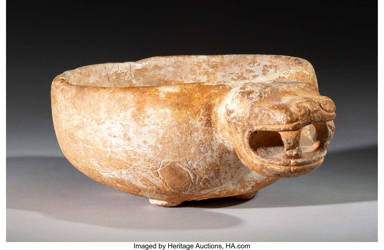A Mixtec or Toltec Alabaster Bowl with Jaguar He: A Mixtec or Toltec Alabaster Bowl with Jaguar Head Mexico, c. 1100-1400 AD Slightly raised on four short tabular feet. The large jaguar head is thrust forward, with open