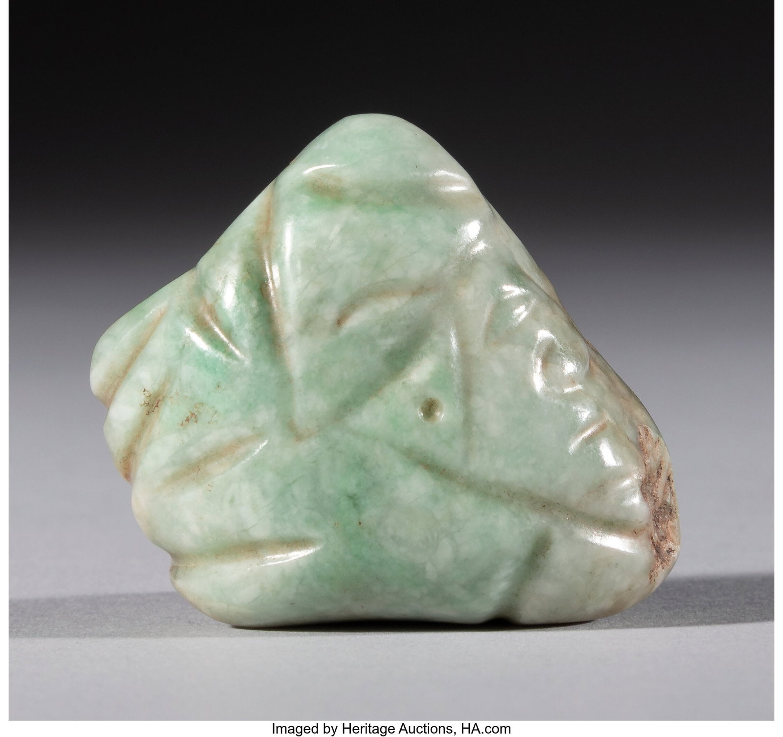 A Maya Head Pendant Mesoamerica, c. 600–800 : A Maya Head Pendant Mesoamerica, c. 600–800 AD Polished light green jade, drilled through the center for suspension. One side is grooved and drilled to create a