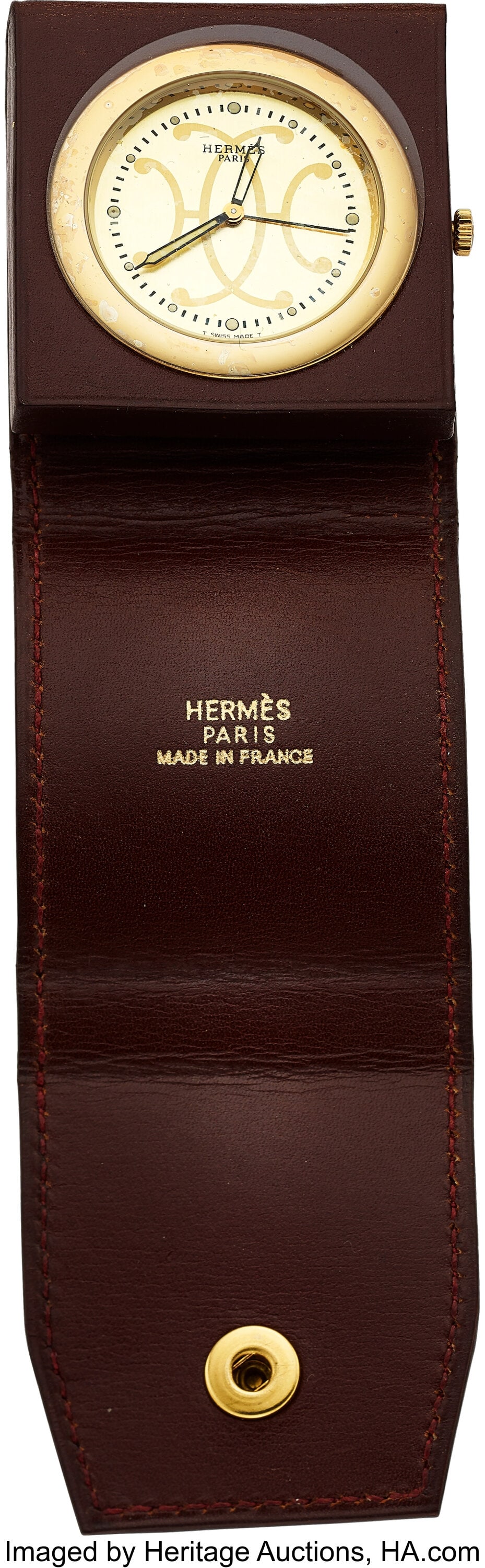 Hermès Brown Leather Folding Travel Alarm Clock: Hermès Brown Leather Folding Travel Alarm Clock Case: round gold-tone clock set into a brown leather folding travel case, signed Hermès Paris Made in France; side crown 