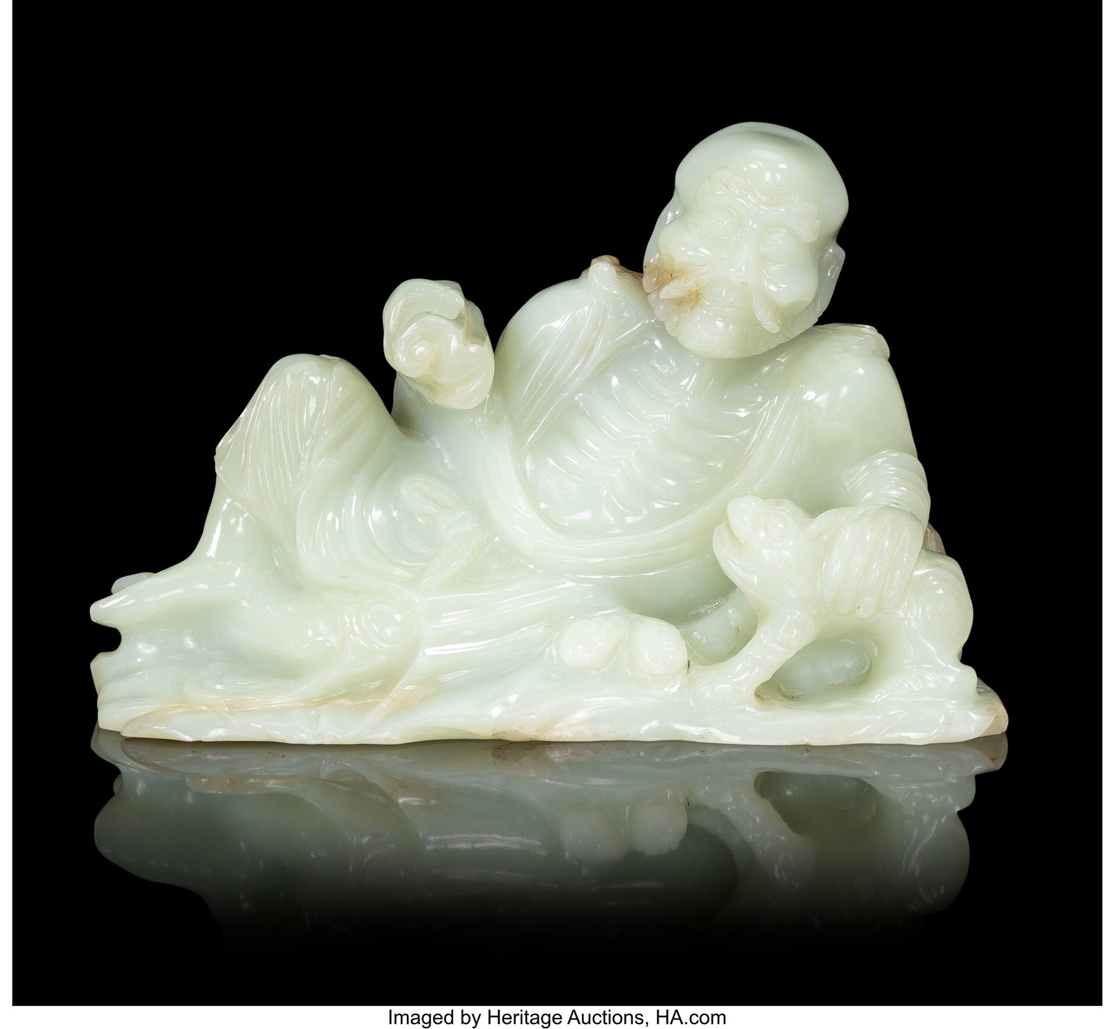 A Chinese Carved Pale Celadon Jade Reclining Fig: A Chinese Carved Pale Celadon Jade Reclining Figure of Luohan, 19th/20th century 7 x 10-1/4 x 3-3/4 inches (17.8 x 26.0 x 9.5 cm) PROVENANCE: Sot