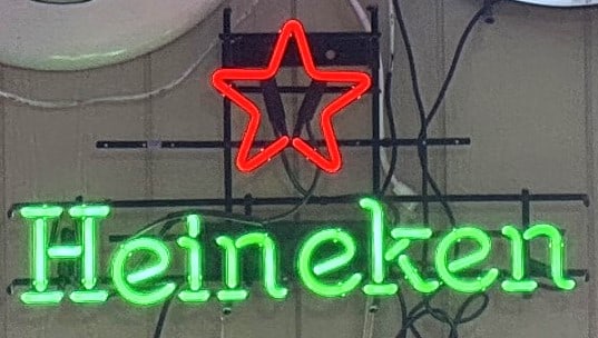 HEINEKEN ANTIQUE NEON: CLASSIC ORIGINAL BEER NEON 17 x 32 At the top, there is a red five-pointed star, which is part of Heineken’s logo.Below it, the word “Heineken” appears in bright green illuminated letters.NE