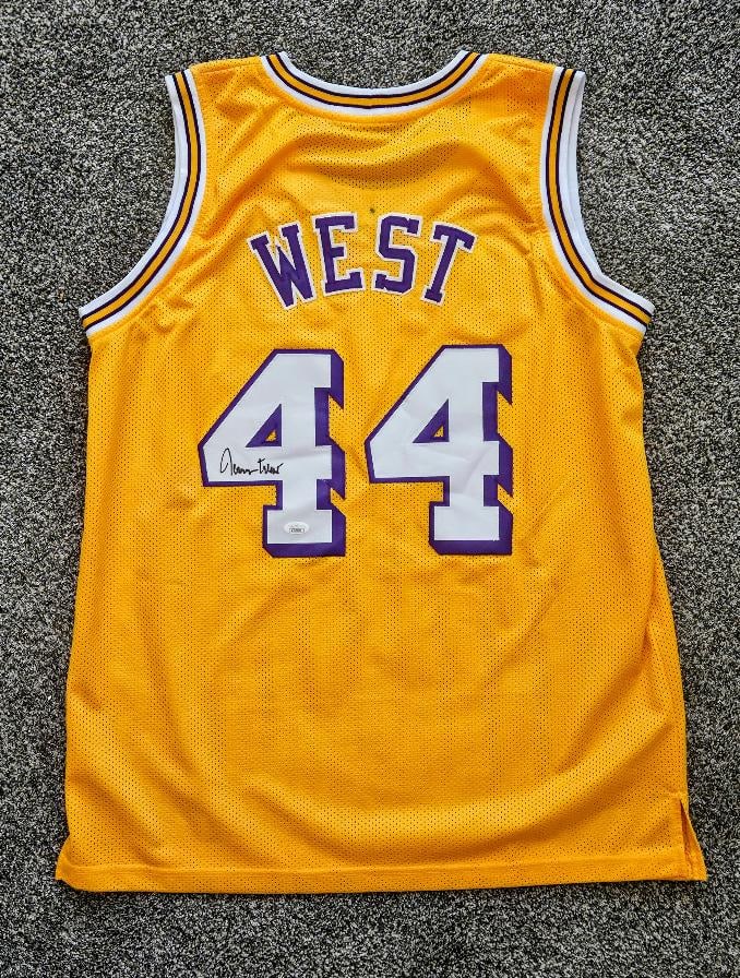 JERRY WEST SIGNED LOS ANGELES LAKERS JERSEY, JSA: JERRY WEST SIGNED GOLD LOS ANGELES LAKERS JERSEY, JSA CERTIFIED! Did you know that Jerry West who is considered one of the greatest ever to step on a basketball court, the NBA logo on every game