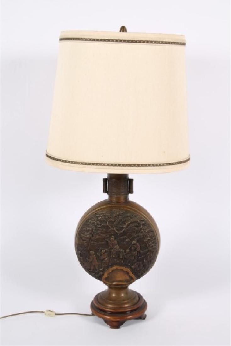 Marbro Lamp Company, Brass Table Lamp: Marbro Lamp Company (America, 20th C.). Brass, wood. Height: 36", Width: 10". Two-light lamp features a Chinese-inspired brass relief disk-shaped body depicting multiple figures traversing through a l