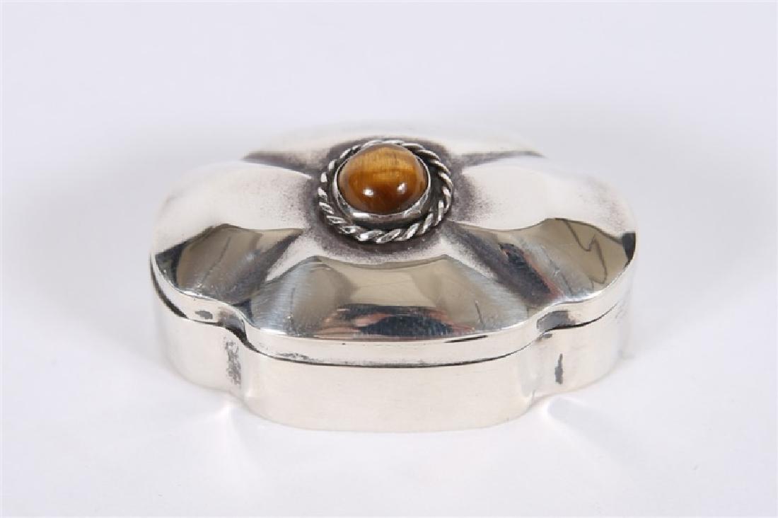 Taxco, Sterling Silver & Tiger's Eye Pill Box: Length: 1 3/4", Depth: 1 1/8", Height: 3/4". Weight: .435 ozt. Hinged box features a central cabochon stone on lid, as well as maker's marks "Taxco Mexico 925" and Taxco Eagle to underside.