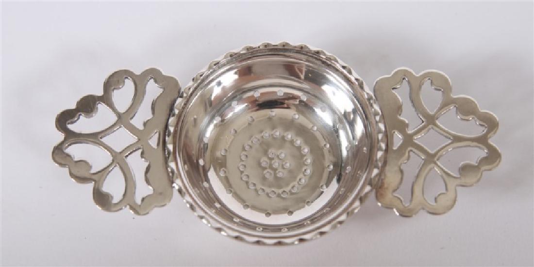 Sterling Silver Lemon or Tea Strainer: Length: 5 1/8", Diameter (of strainer): 2 /12", Height: 3/4". Weight: 1.415 ozt. Strainer features a central radial perforated dish flanked by two handles with scroll motif. Item appears to be unmarke