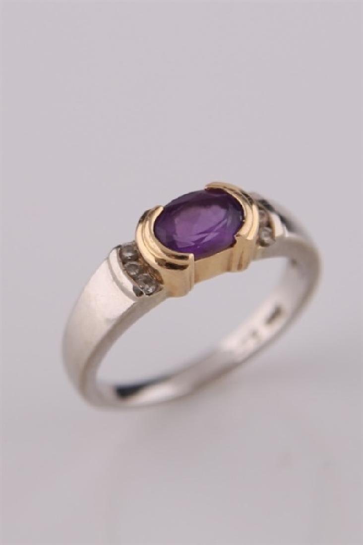 14kt White and Yellow Gold Amethyst Ring: 14kt white and yellow gold ring with amethyst stone. Center amethyst stone flanked by six moissanite stones. Interior of band marked "14K". Size: 6 1/2. Weight: 4 g.