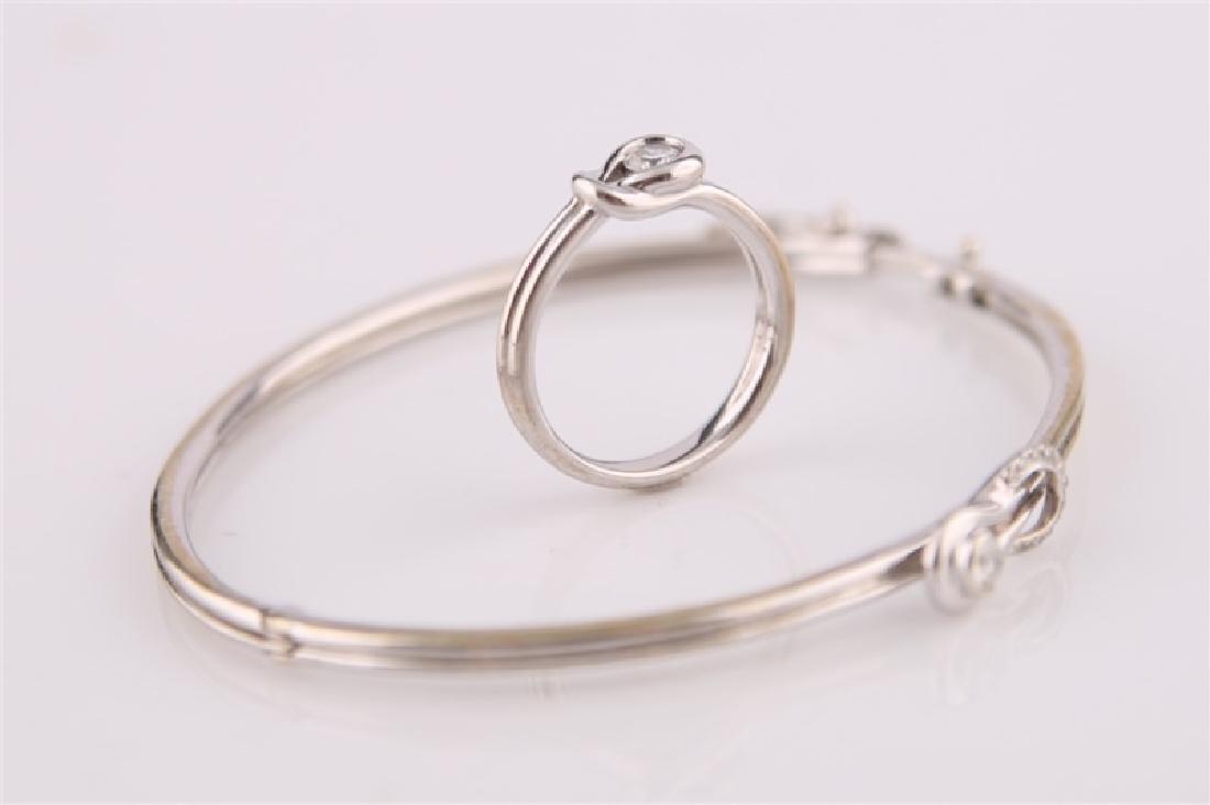 14kt White Gold Ring with Diamond and Bracelet: 14kt white gold ring with center diamond. Ring in a loop design. Interior of band marked "14K". Size: 6 3/4. Weight: 4.2 g. Matching 925 sterling silver bracelet with diamonds. Fourteen (14) diamonds