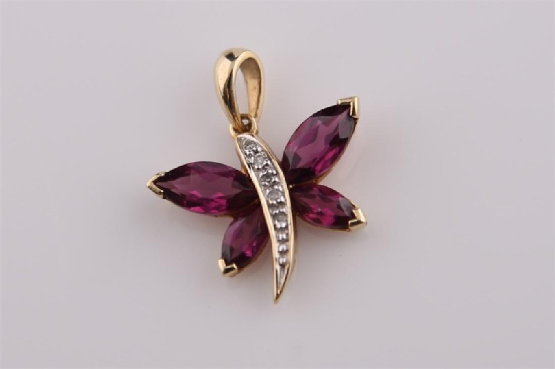10kt Yellow Gold Purple Stone Butterfly: 10kt yellow gold butterfly with burgundy colored stones (possibly amethyst or garnet) as wings. Body of butterfly is 10kt yellow gold and outlined with diamond chips. Butterfly is stamped with 10K. WE