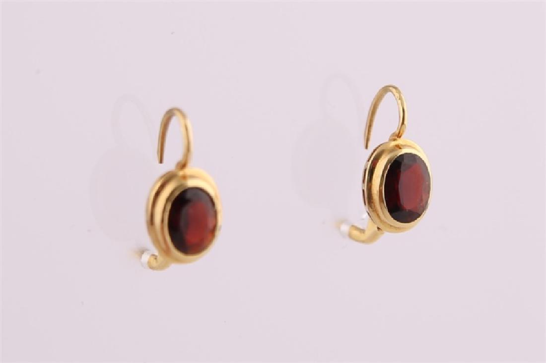 18kt Yellow Gold and Garnet Earrings: 18kt yellow gold earrings with garnet stones. Lever back clasp. Clasp marked "750". Length: 3/4". Weight: 3.3 g.