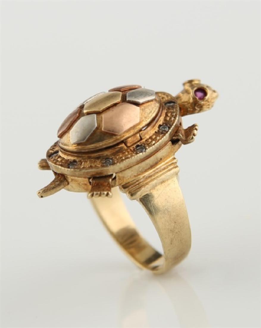 10kt Tri-Tone Articulated Turtle Poison Ring: 10kt tri-tone articulated turtle poison ring. Yellow gold, rose gold, and white gold. Turtle has ruby eyes. Shell of turtle flips up. Turtle's legs, head, and tail are articulated. Interior of band ma