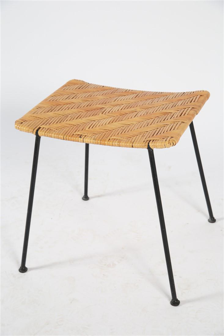 Style Of Paul McCobb, Stool: Stool. Straw and iron. Height: 17 3/4", Length: 17 1/2", Width: 14". Stool has four black wrought legs and a lacquered straw woven seat. Stool is in the style of Paul McCobb.