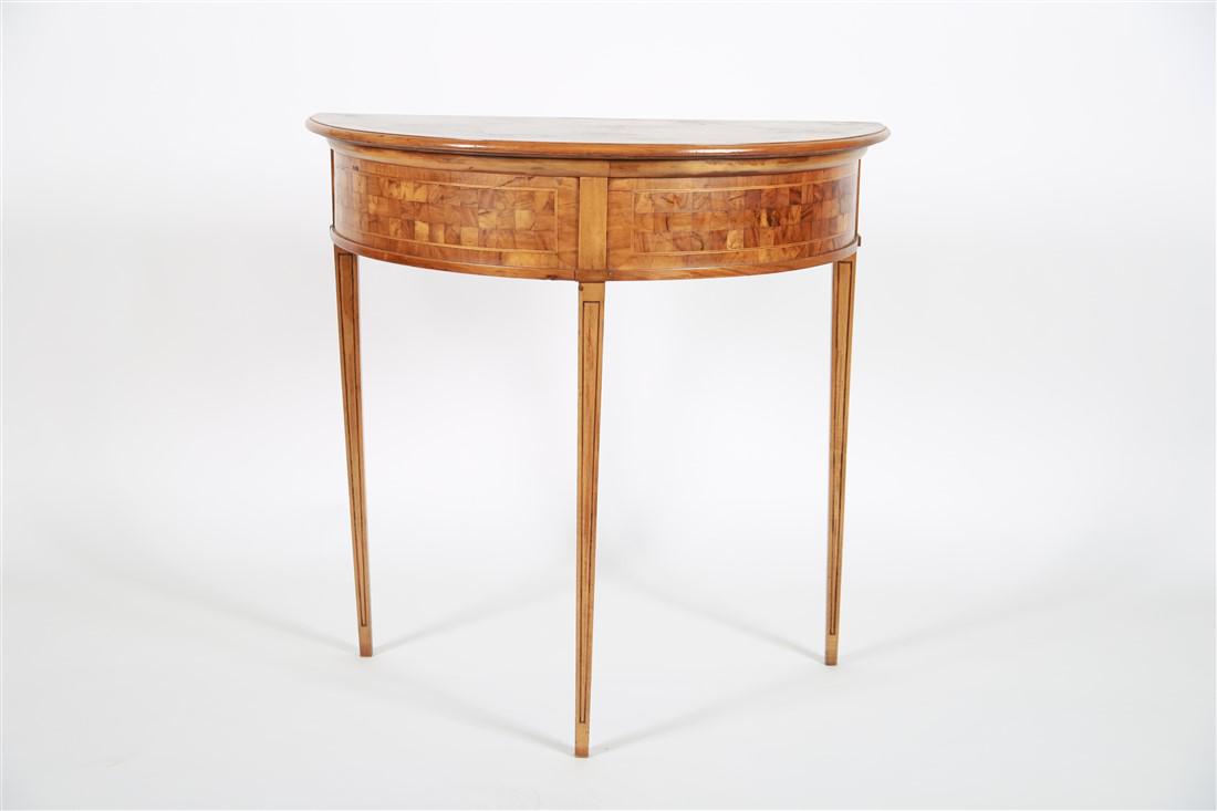 Biedermeier Inlaid Demilune Table: c. late 19th - early 20th century. Inlaid wood. Height: 32 1/2", Length: 32 1/2", Depth: 18". Checkered inlaid wood demilune table. On three tapered legs. Appears unmarked. Provenance: From the collec