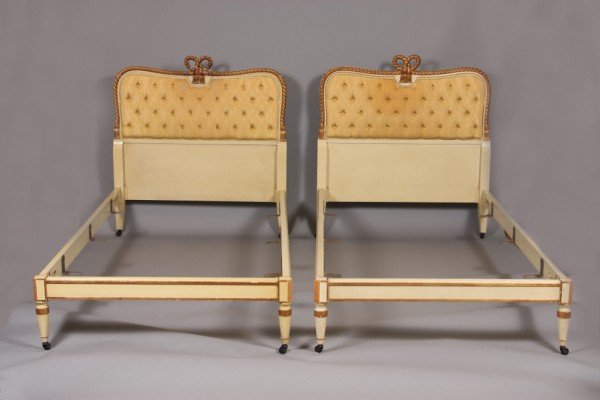 Pair Louis XVI Style Gilt, Painted and Upholstered : With bow tie and rope twist border, surrounding a button tufted head board, and low paneled foot board, Baker furniture. H: 42" W: 42" Condition: Wear to gilt and painted finish.
