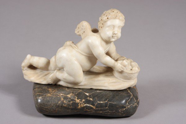 Carved Marble Cupid, Continental, 19th Century: Continental, 19th century. Reclining cupid with a fruit basket set on an oval form marble base. Dimensions: H: 12 1/2" L: 13 1/2" Condition: Appears fine, has 2 small chips.