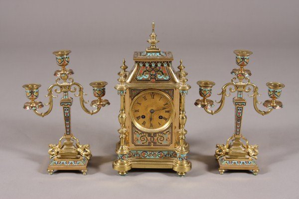 Second Empire Gilt Bronze & Champleve Enamel Clock: Clock garniture, probably French. Early 20th century. The clock with turned finial over flaring square top above rectangular case centering Roman numeral dial and flanked by turned pilasters. With ove