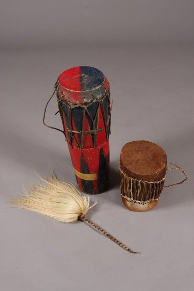 Two Wood & Hide Drums, African, 20th C. With a Dru: African, 20th century. One painted with a red and blue motif. The other with hide top and bottom. Together with a drum mallet. Tallest Height: 21 3/4" Condition: The painted finish is chipped and worn