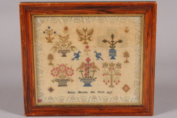Needlework Sampler, Inscribed "Betty Hewitt her wor: Dated 1857. With a flowering vine border surrounding flowering urns and birds. Dimensions: 12" x 14" Condition: Yellowed overall.