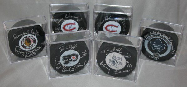 Collection of Six Autographed Hockey Pucks: Autographed by Hockey Hall of Fame members. Signatures include: Johnny Bower HOF 1976, Tony Esposito HOF 1988, Bernie Patent HOF 1984, Jean Beliveau HOF 1972 and others. Pucks signed various forms of 