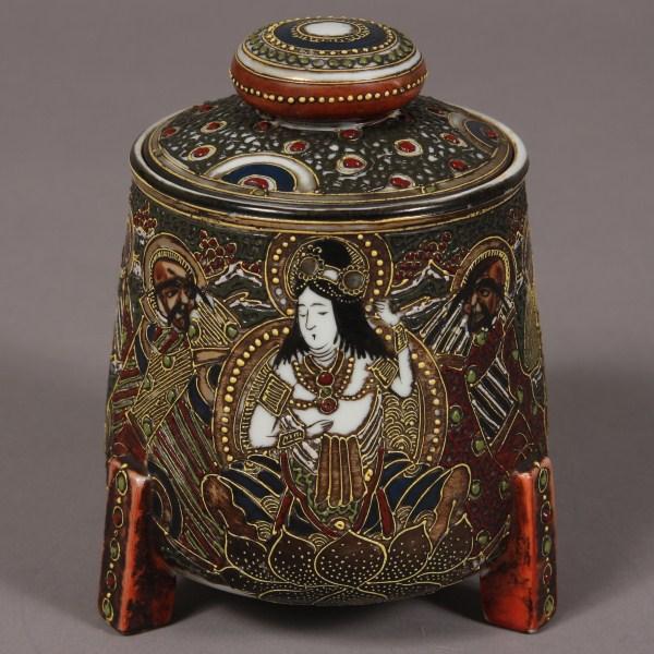 Satsuma Porcelain Humidor, Japanese, 20th C. Cylin: Cylindrical form with bracket feet and cover. Decorated with figures against a gilt and jeweled ground. Height: 7 1/2". Condition: The cover is chipped. A piece is broken out and repaired. Paint faded